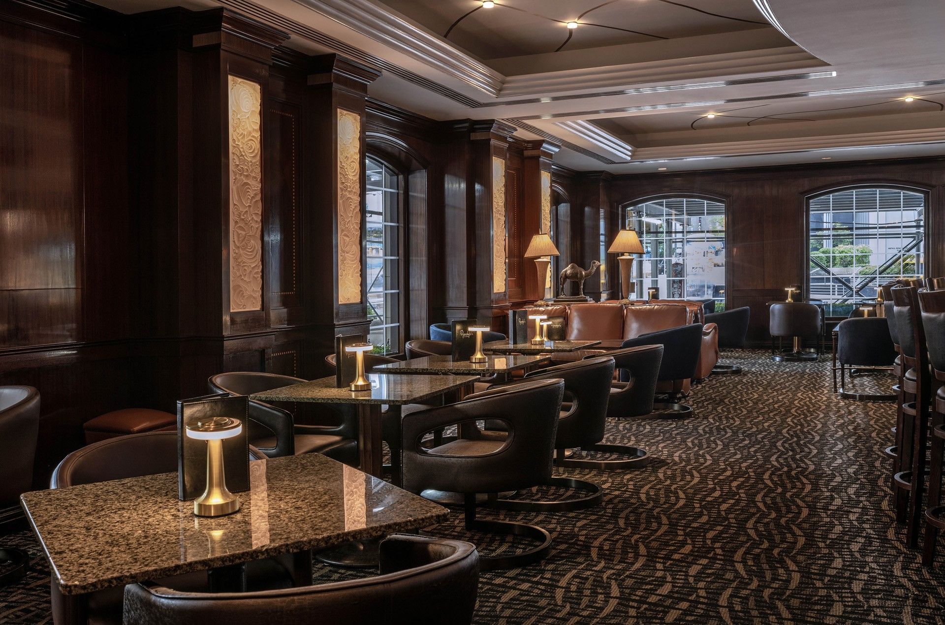 Wood-paneled Randolph's Bar & Lounge with marble tables and warm lighting at Warwick New York