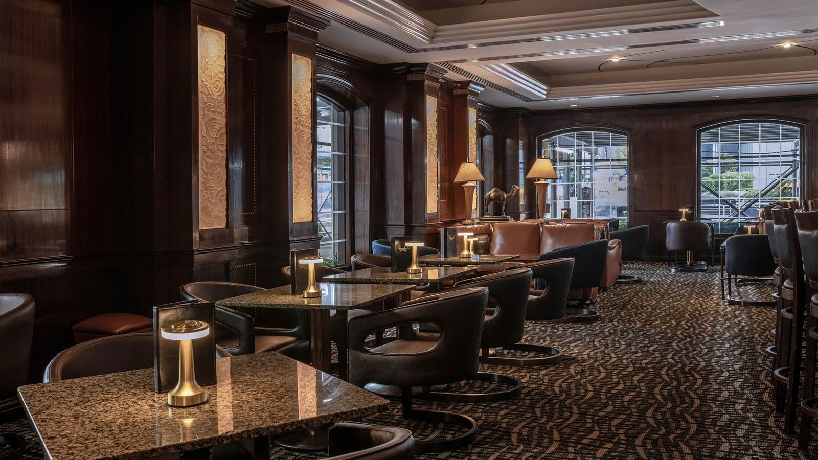 Dimly lit lounge featuring dark wood paneling and tables & cozy seating in Randolph's Bar & Lounge at Warwick New York