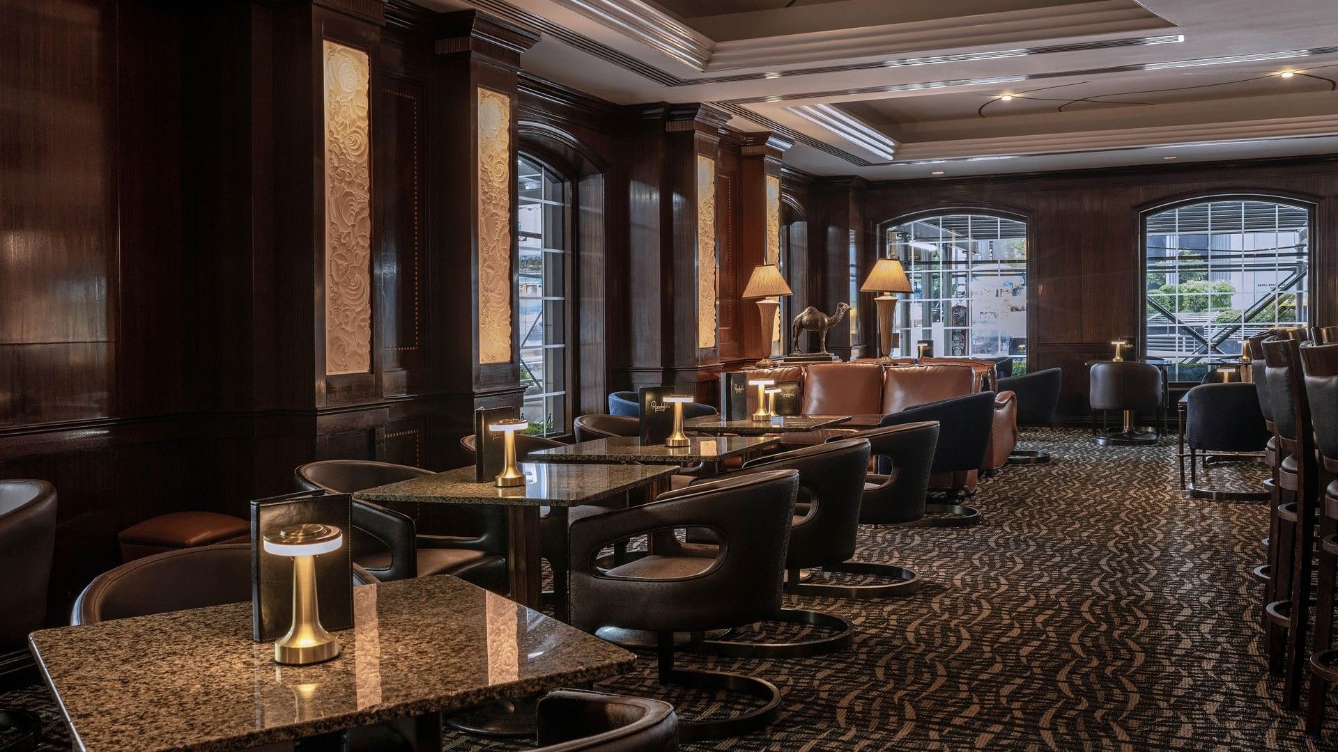 Dimly lit lounge featuring dark wood paneling and tables & cozy seating in Randolph's Bar & Lounge at Warwick New York