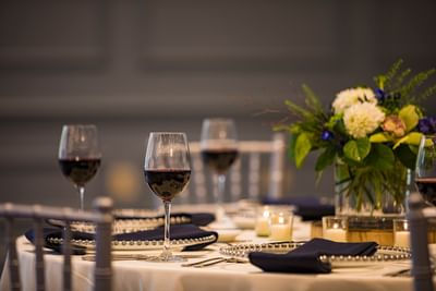 Elegant event table featuring wine glasses and a floral centerpiece in the event space at Sable Oaks Weddings and Events