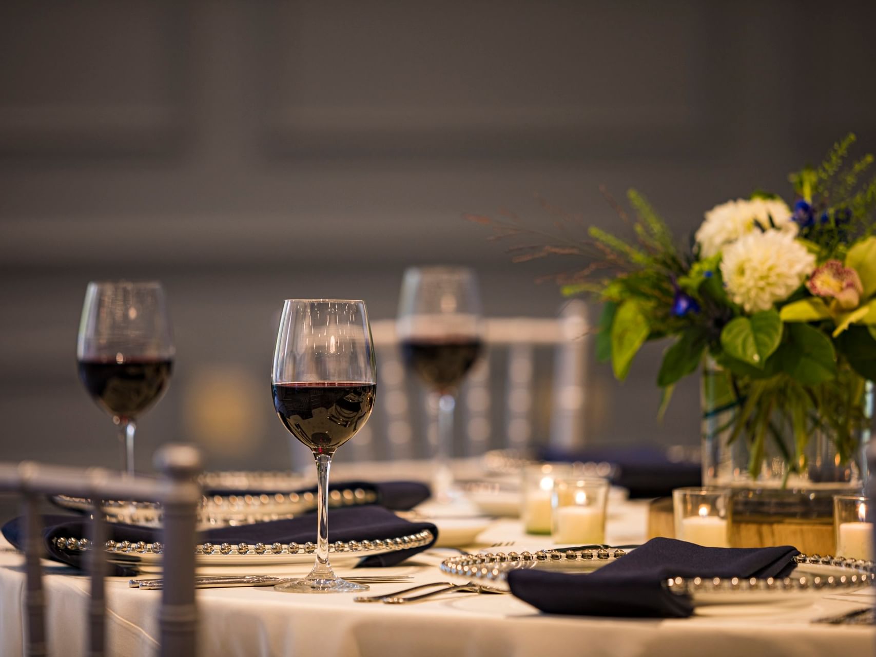 Elegant event table featuring wine glasses and a floral centerpiece in the event space at Sable Oaks Weddings and Events