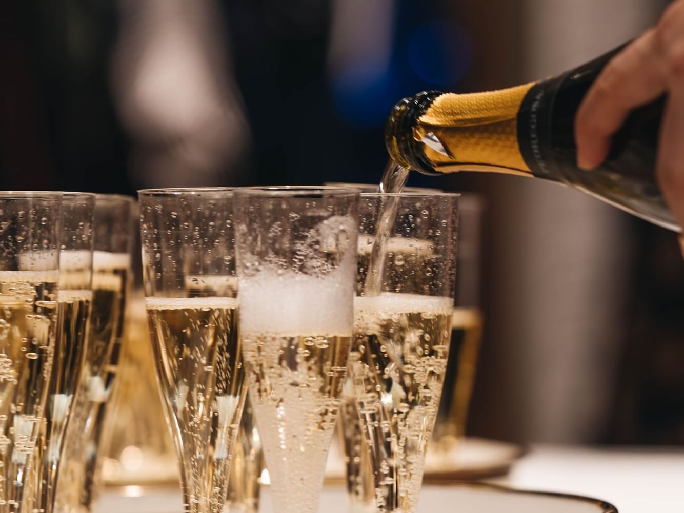 A man pouring Champagne into Champagne glasses at Pine Inn