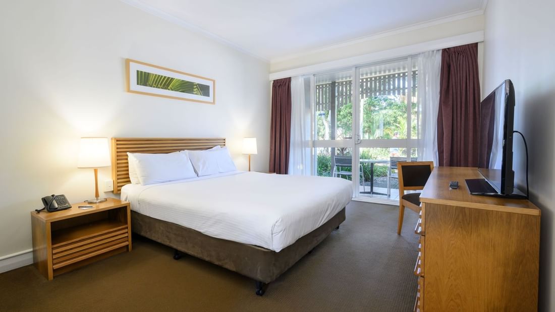 Bright resort room with queen bed, wooden furnishings, and garden view at Novotel Sunshine Coast Twin Waters.
