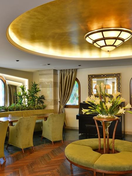 Lobby Lounge features green armchairs by an round table under a golden ceiling at Warwick Ankara