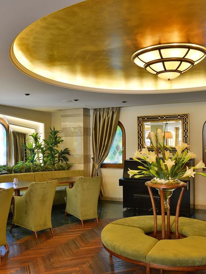 Lobby Lounge features green armchairs by an round table under a golden ceiling at Warwick Ankara