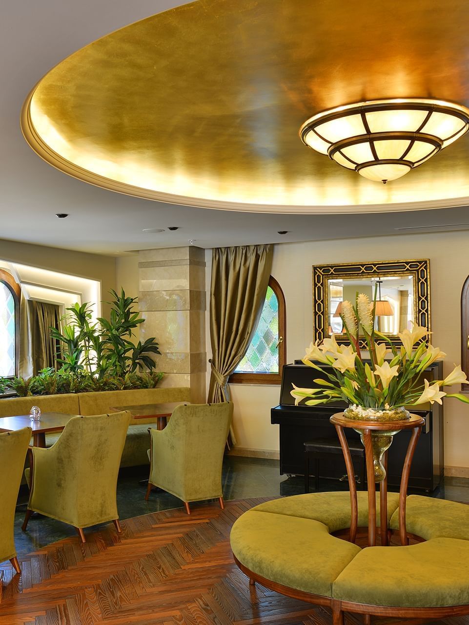 Lobby Lounge features green armchairs by an round table under a golden ceiling at Warwick Ankara