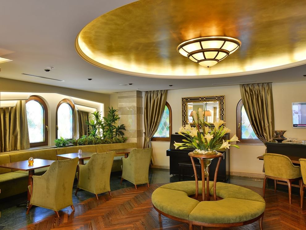 Lobby Lounge features green armchairs by an round table under a golden ceiling at Warwick Ankara