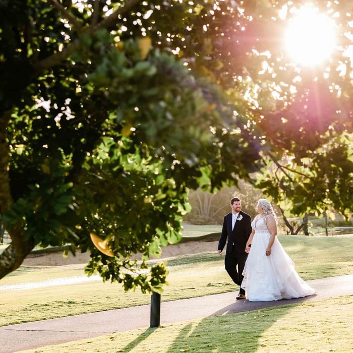 A bride and groom walking hand in hand near Mercure Kooindah Waters