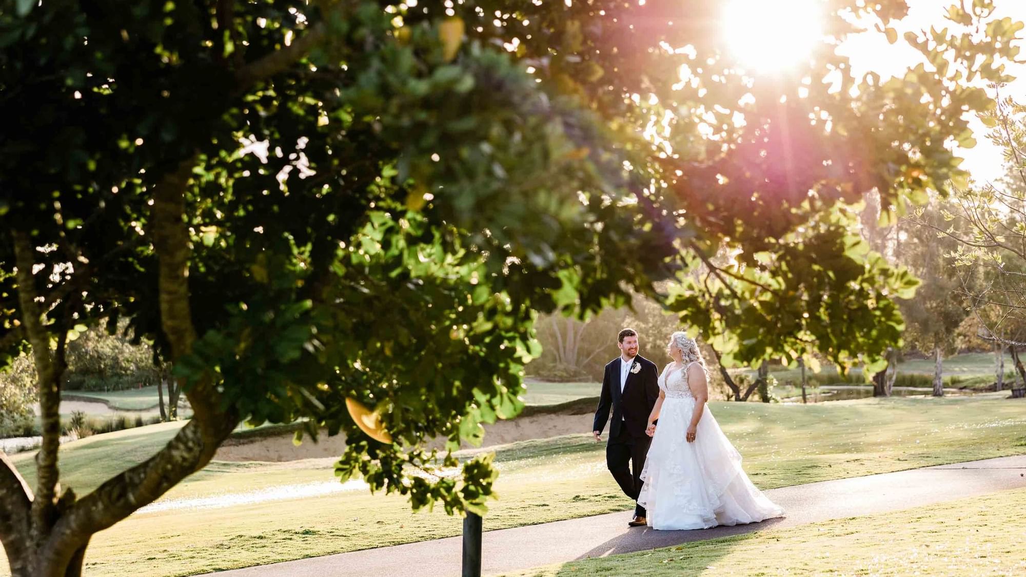 A bride and groom walking hand in hand near Mercure Kooindah Waters