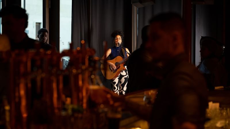 Women with a guitar performing live on a stage in an event at The Londoner Hotel