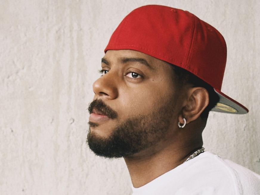 Male artist in red cap and white shirt gazing to the side for Bryson Tiller - The Neo Trapsoul Tour 2027