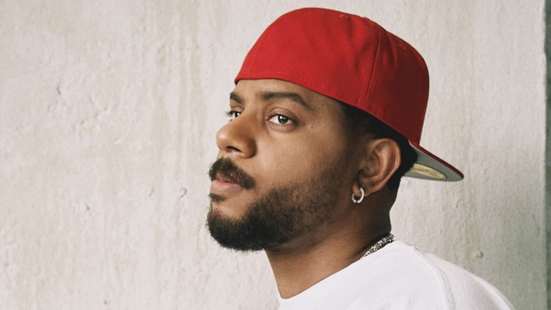 Male artist in red cap and white shirt gazing to the side for Bryson Tiller - The Neo Trapsoul Tour 2027