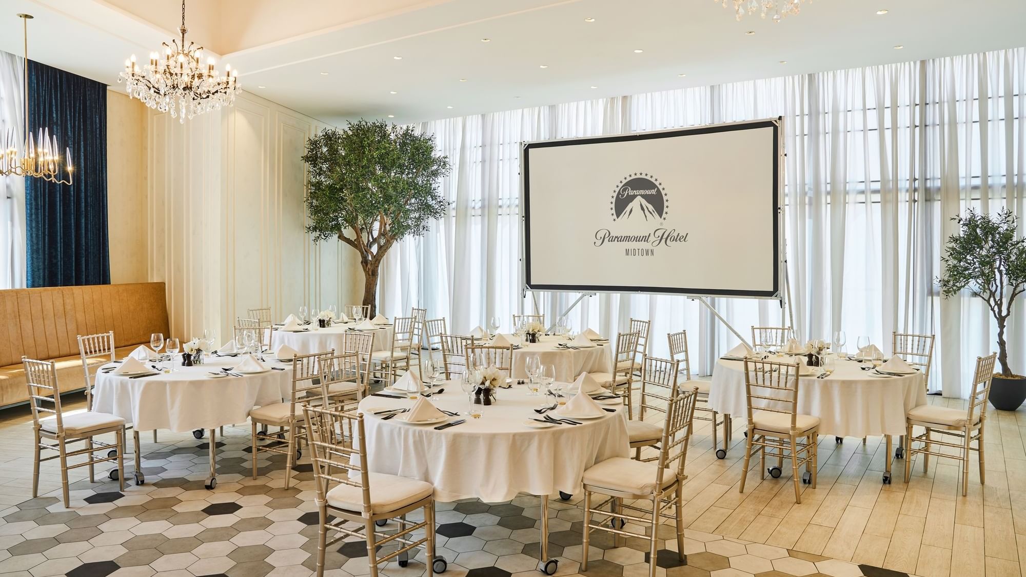 Stylish event setup at Paparazzi restaurant venue, Paramount Hotel Midtown, with round tables and a projector screen