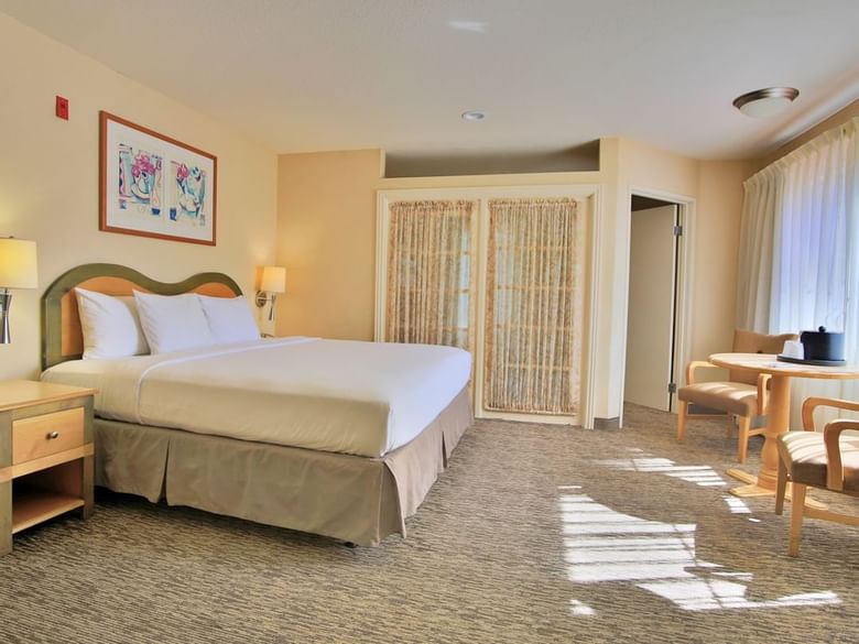 A hotel room with a bed, nightstand, desk, and chair.