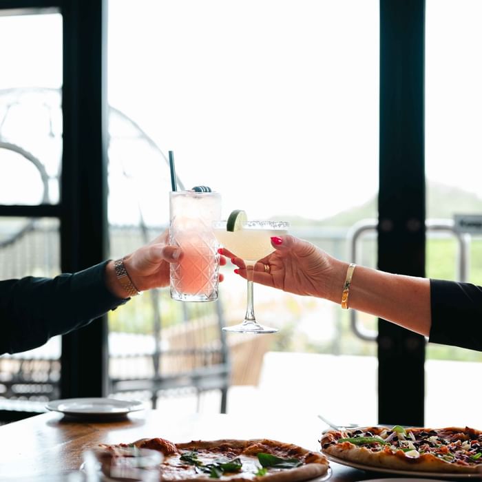 Two hands toasting with cocktails in Karinyas Restaurant at Mercure Kooindah Waters