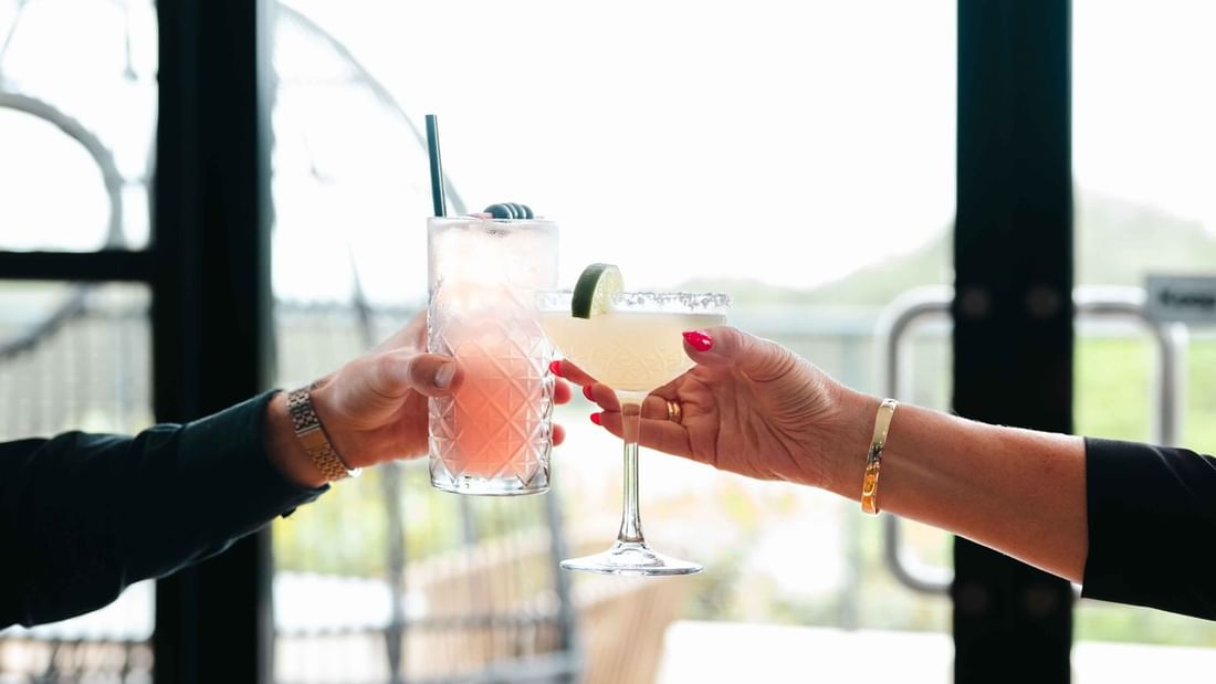Two hands toasting with cocktails in Karinyas Restaurant at Mercure Kooindah Waters