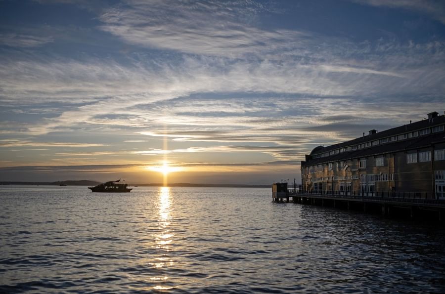 Sunset over water with a boat and building at Warwick Seattle.