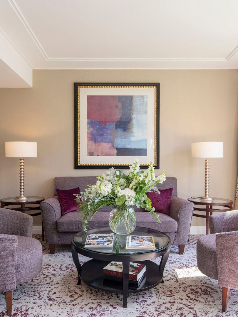 Grey sofa surrounding a glass coffee table by tall lamps in The Montaigne Suite at Warwick Paris Champs Elysées