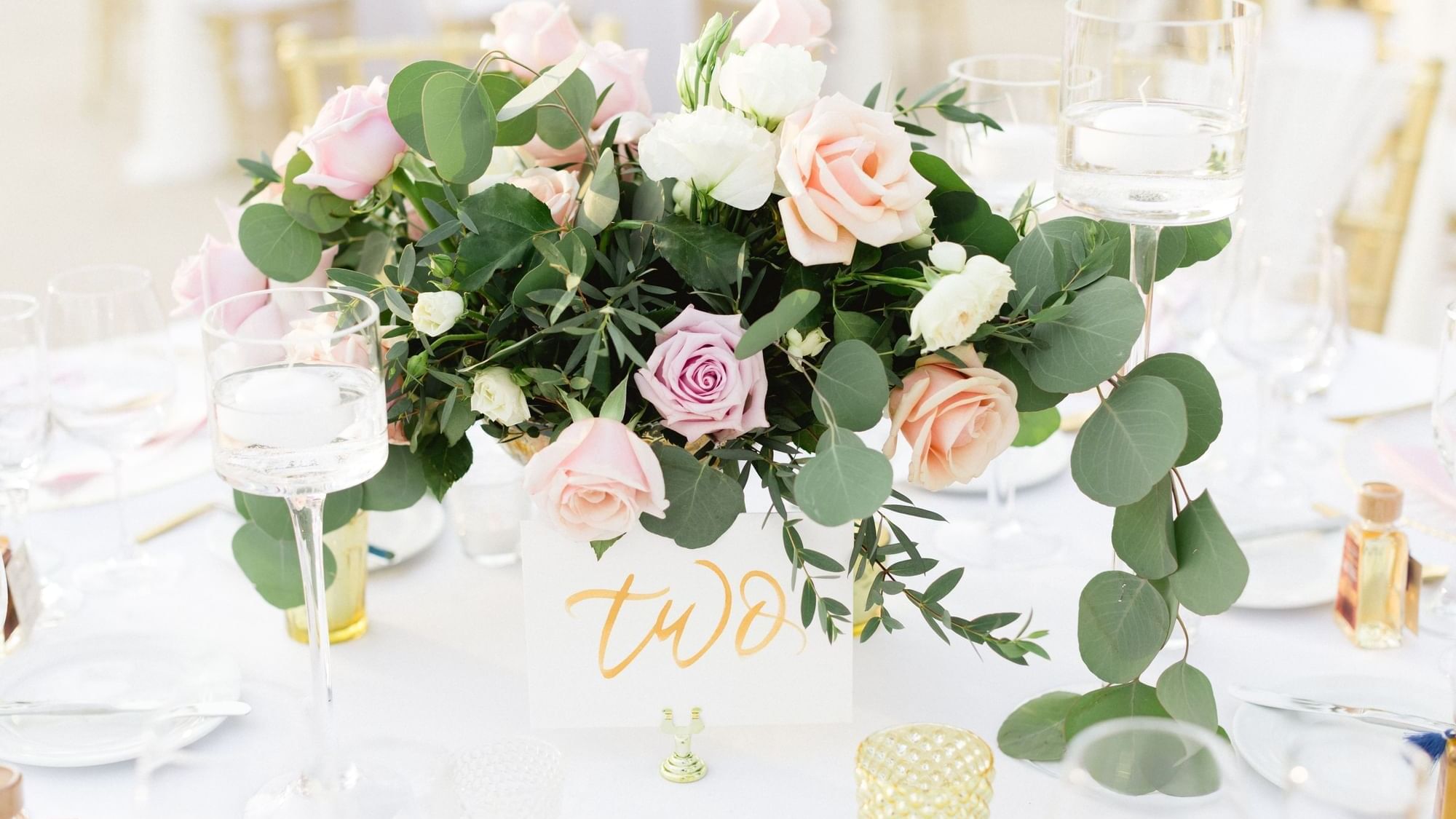 Elegant wedding centerpiece with pink and white roses, eucalyptus leaves, and floating candles at The Explorean Resorts