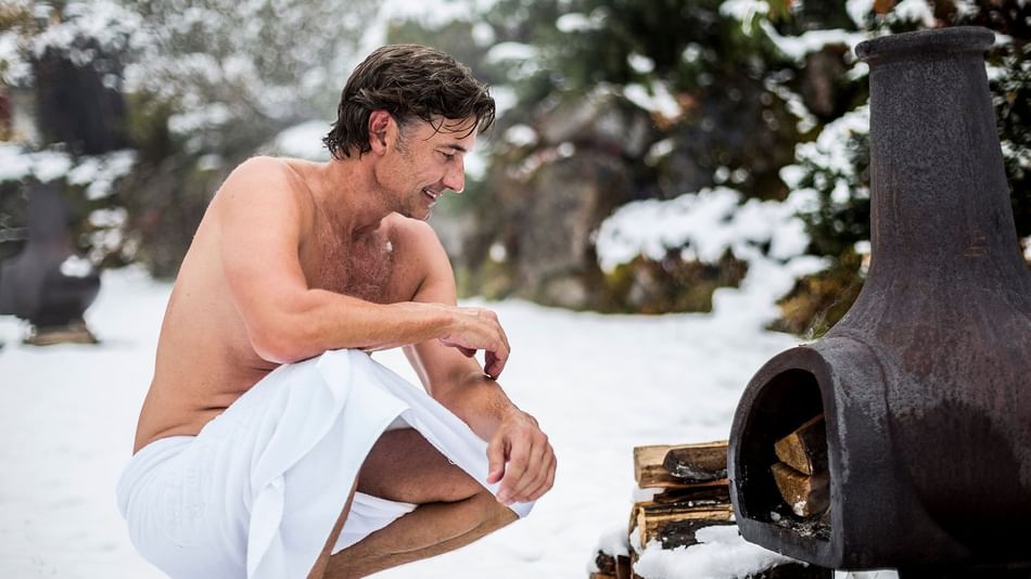 Gast vor Heizofen im Winter im Aussenbereich im Wellnesshotel Liebes Rot Flüh, Tannheimer Tal