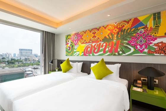 Twin beds & a large wall picture in a room at Maitria Hotel