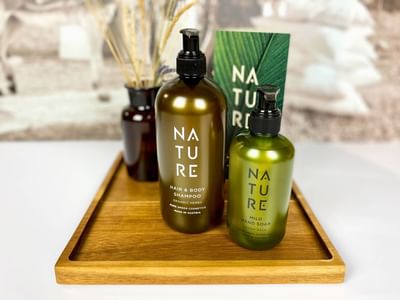 Two eco-friendly Nature cosmetic bottles on a wooden tray at the Avaneo Hotel Marktredwitz