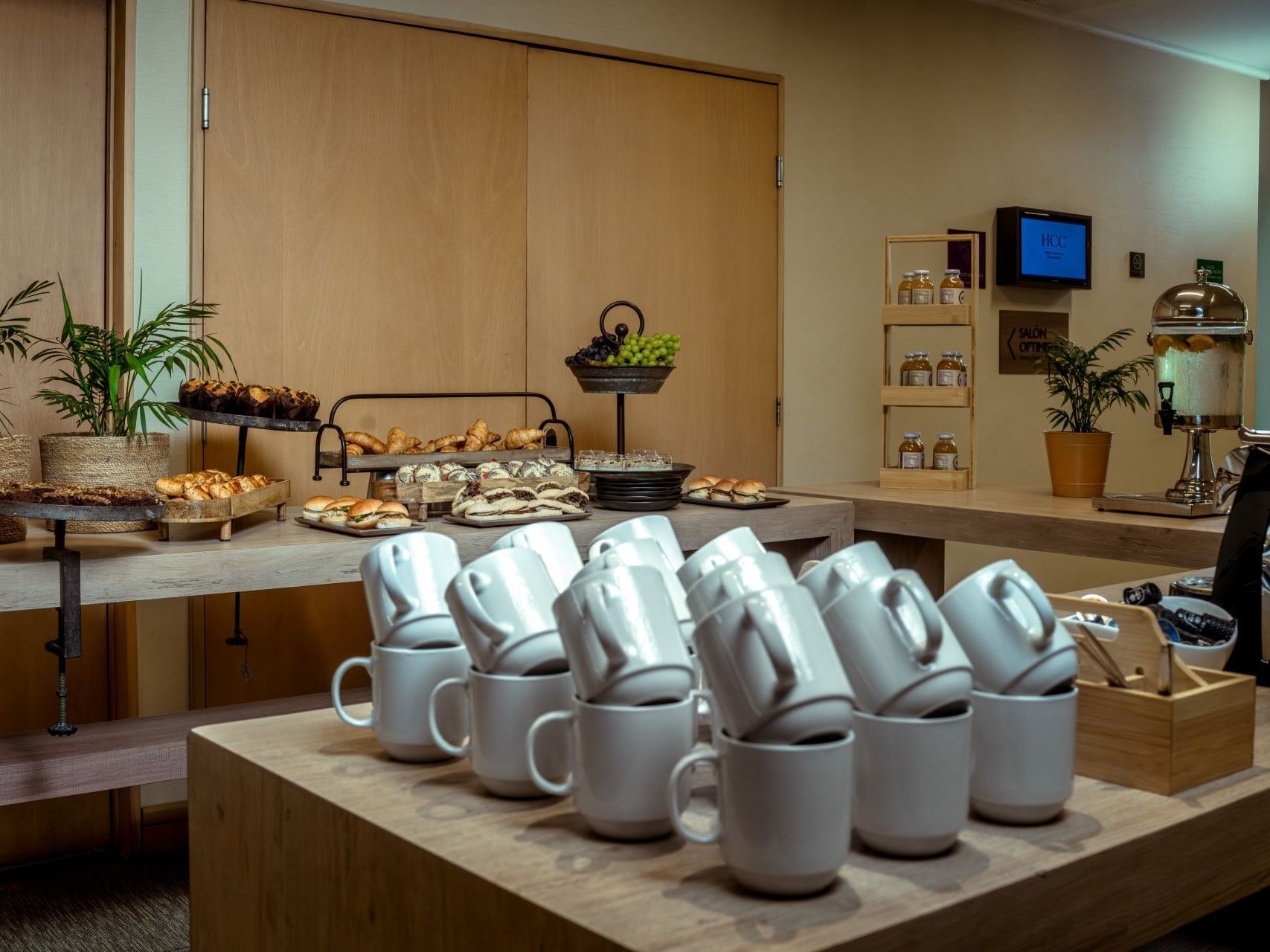 Zona de bufé con bollería, fruta y tazas blancas apiladas en el hotel HCC Costanera Concepción.