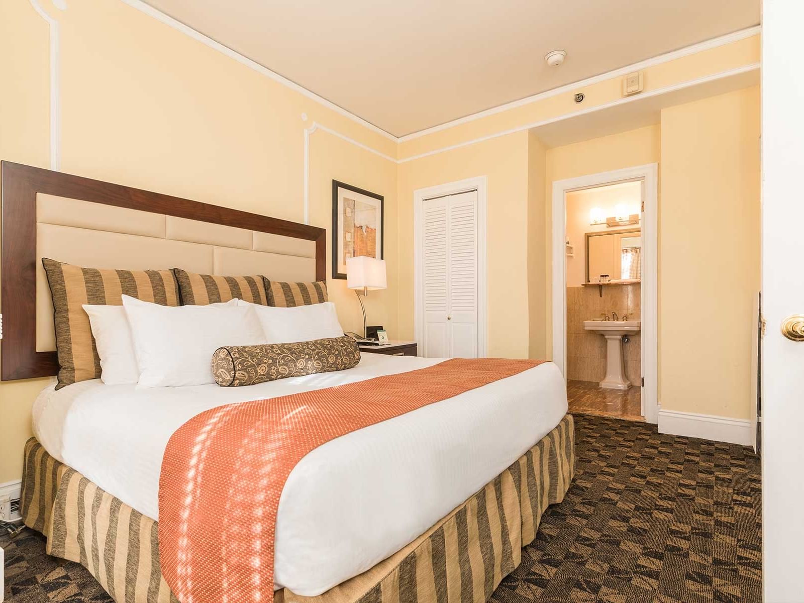 Bedroom with a large bed, pillows, and an open door to a bathroom at Pickwick San Francisco.