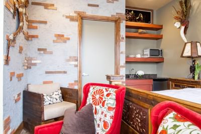 Two red armchairs with comfy pillows by the bed in King Premiere Wild Wild West at Retro Suites Hotel