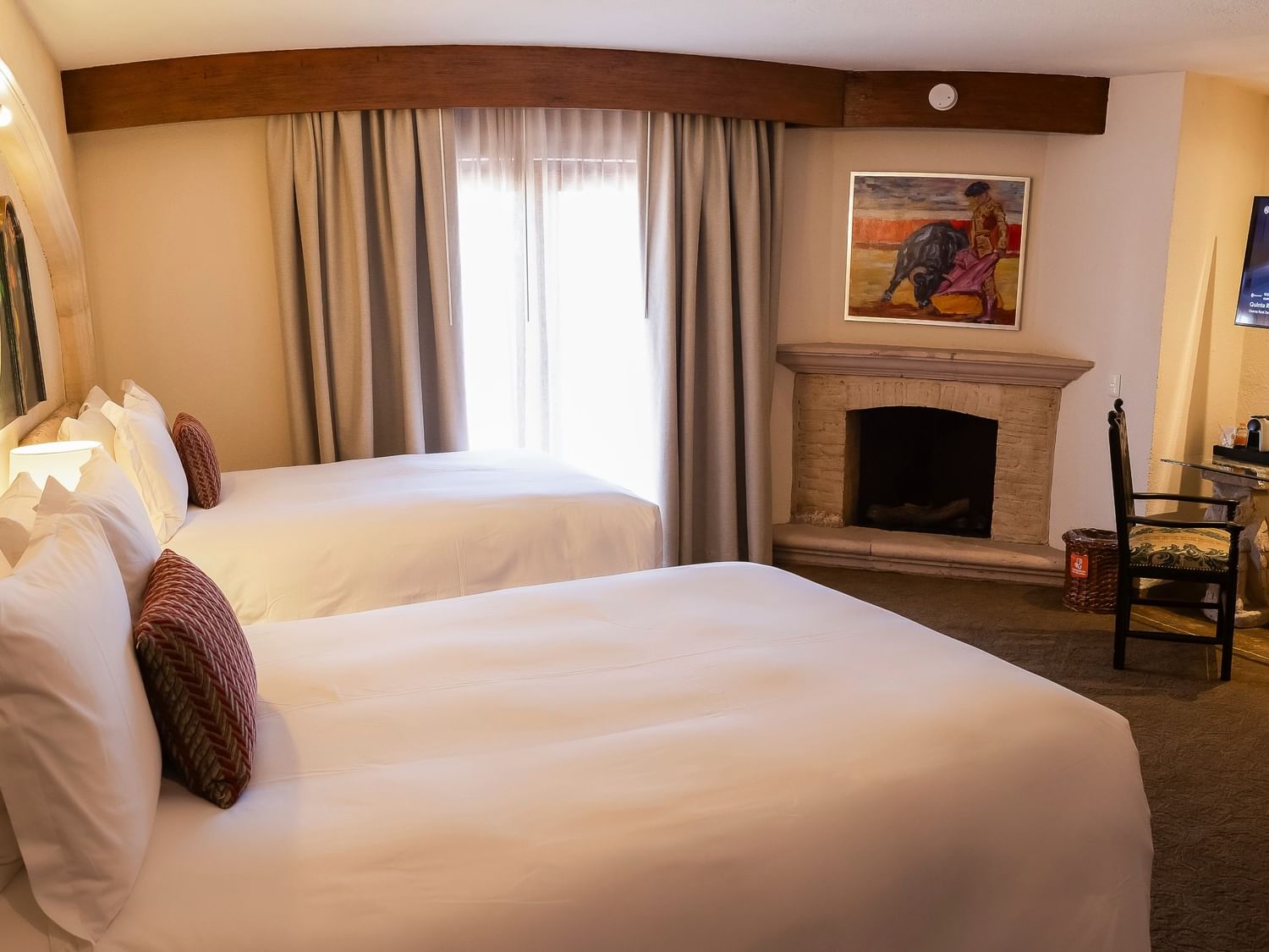 Spacious master suite with two double beds, fireplace, and work desk at Quinta Real Zacatecas