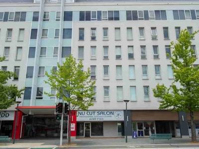 Exterior of Student Living Academie House building with storefronts and trees.