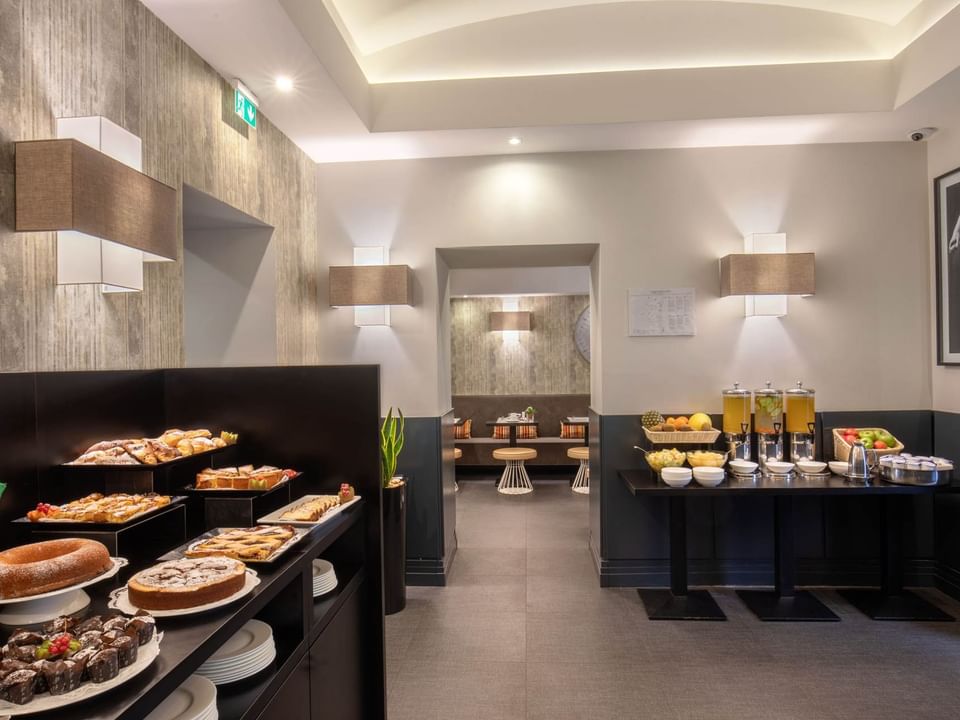 A breakfast room showcasing a buffet feturing pastries, fruit, and drinks, with stylish lighting at The Republic Hotel