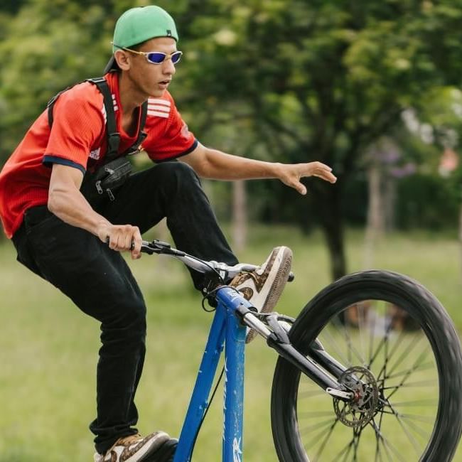 Man performing a trick on a blue bicycle in a grassy field for Everything You Need To Know About The Bracknell Cycle Festival!