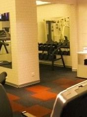 Dumbbells on racks in a gym featuring mirrors and exercise bikes by white pillars at Warwick Ankara
