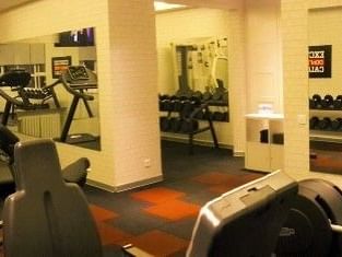 Dumbbells on racks in a gym featuring mirrors and exercise bikes by white pillars at Warwick Ankara