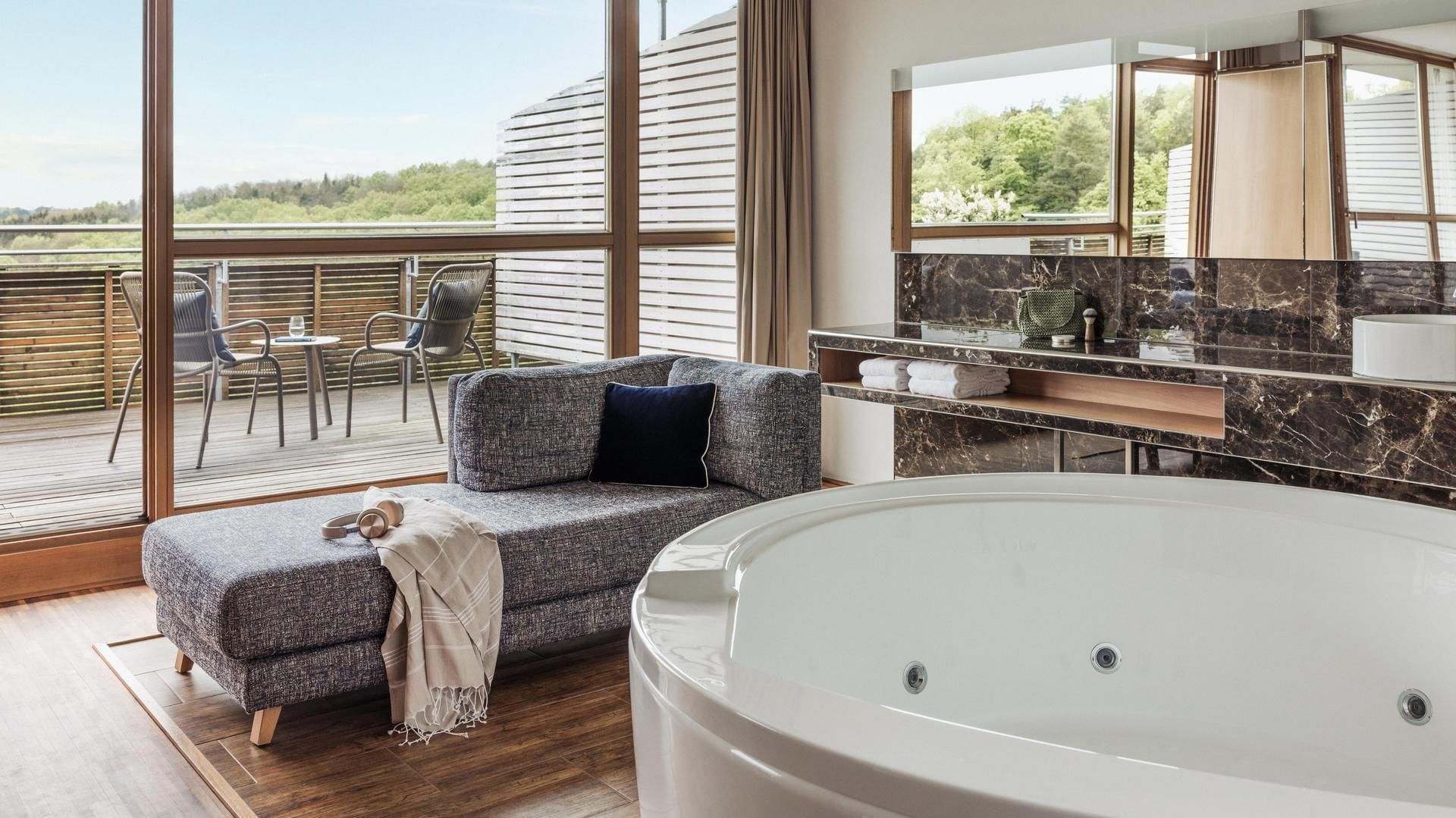 Modernes Badezimmer mit freistehender Badewanne, Lounge-Sitzbank und Balkon mit Ausblick.