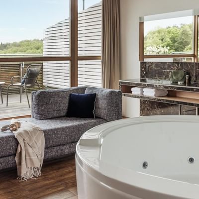 Modernes Badezimmer mit freistehender Badewanne, Lounge-Sitzbank und Balkon mit Ausblick.