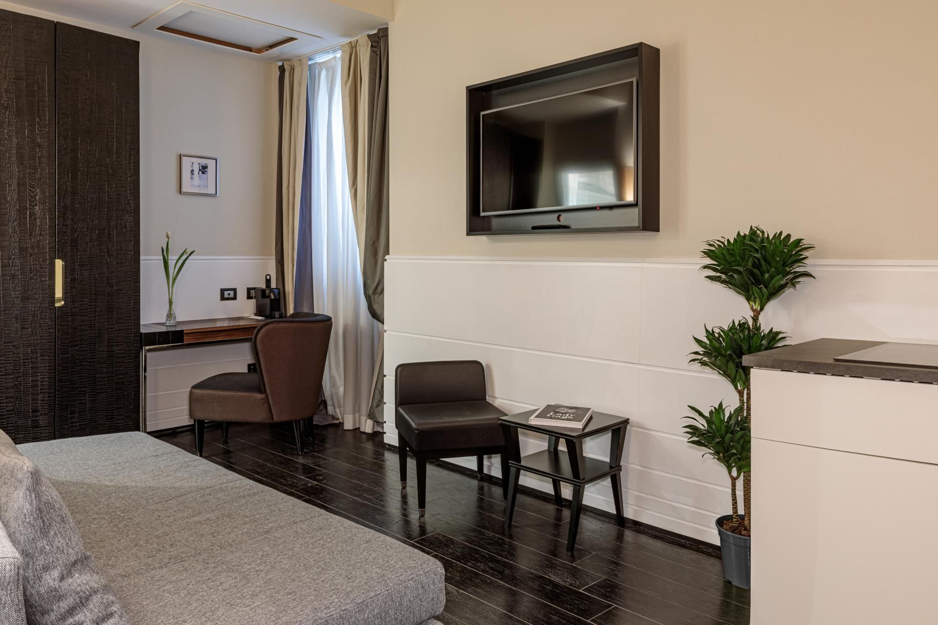 Cozy Smart Room at The Independent Suites with a gray sofa, chair, a wall-mounted TV, and natural light