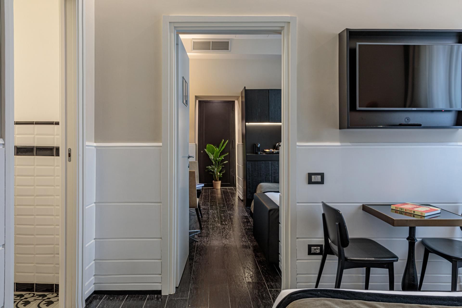 Modern Family Room at The Independent Suites with bedroom view into a living area with dark floors & kitchenette