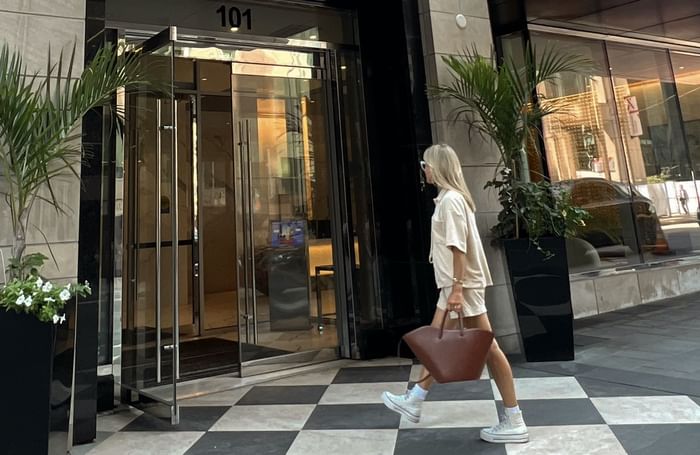 A woman in casual clothes walks past a glass-door building labeled 101 near ReStays Ottawa