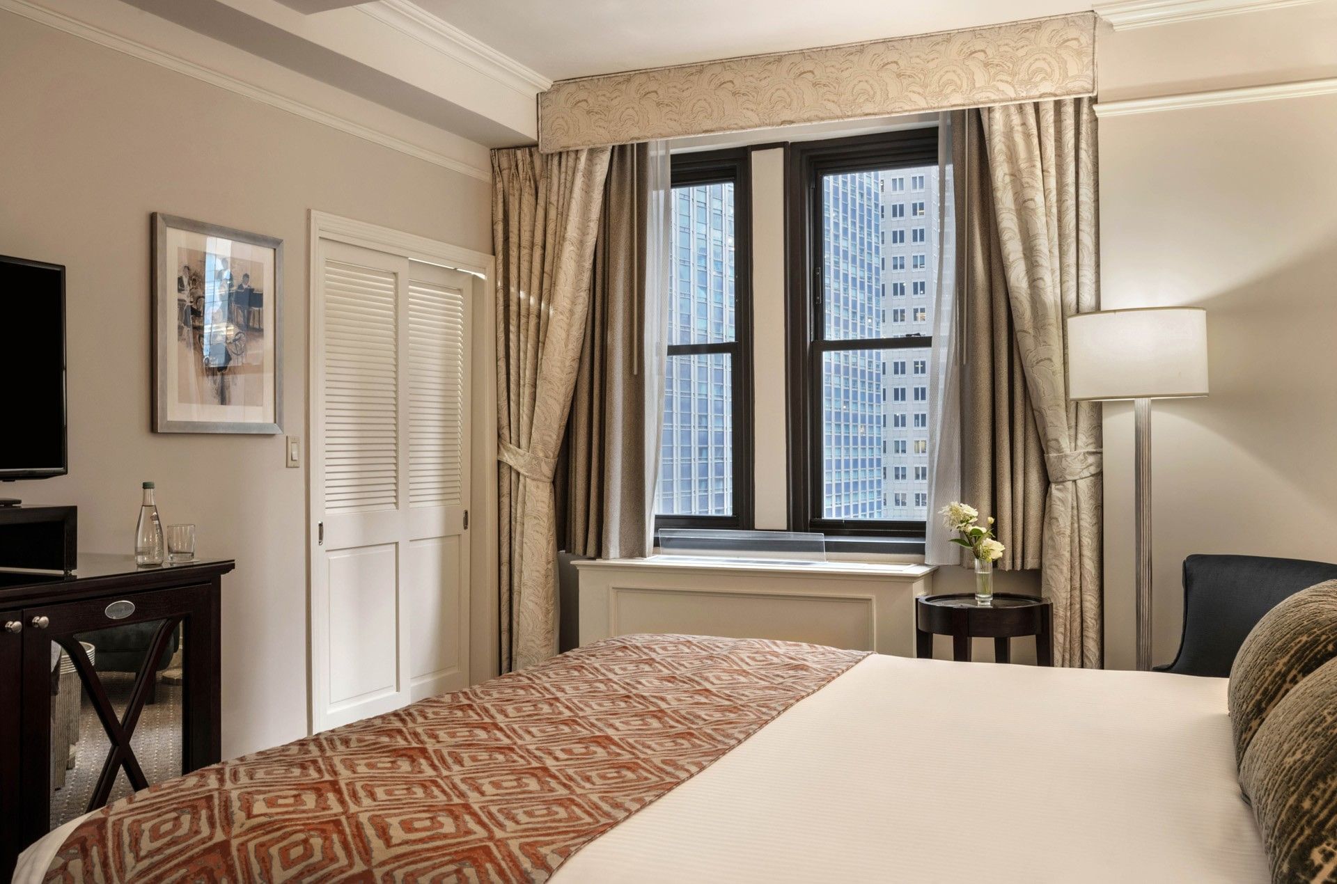 Premier City view room corner view of king bed & louvered closet doors, and city view windows at Warwick New York