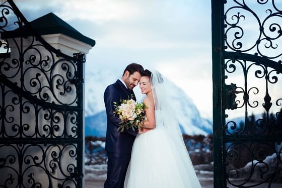 A wedding couple posing by a gate outside at Schloss Hotel
