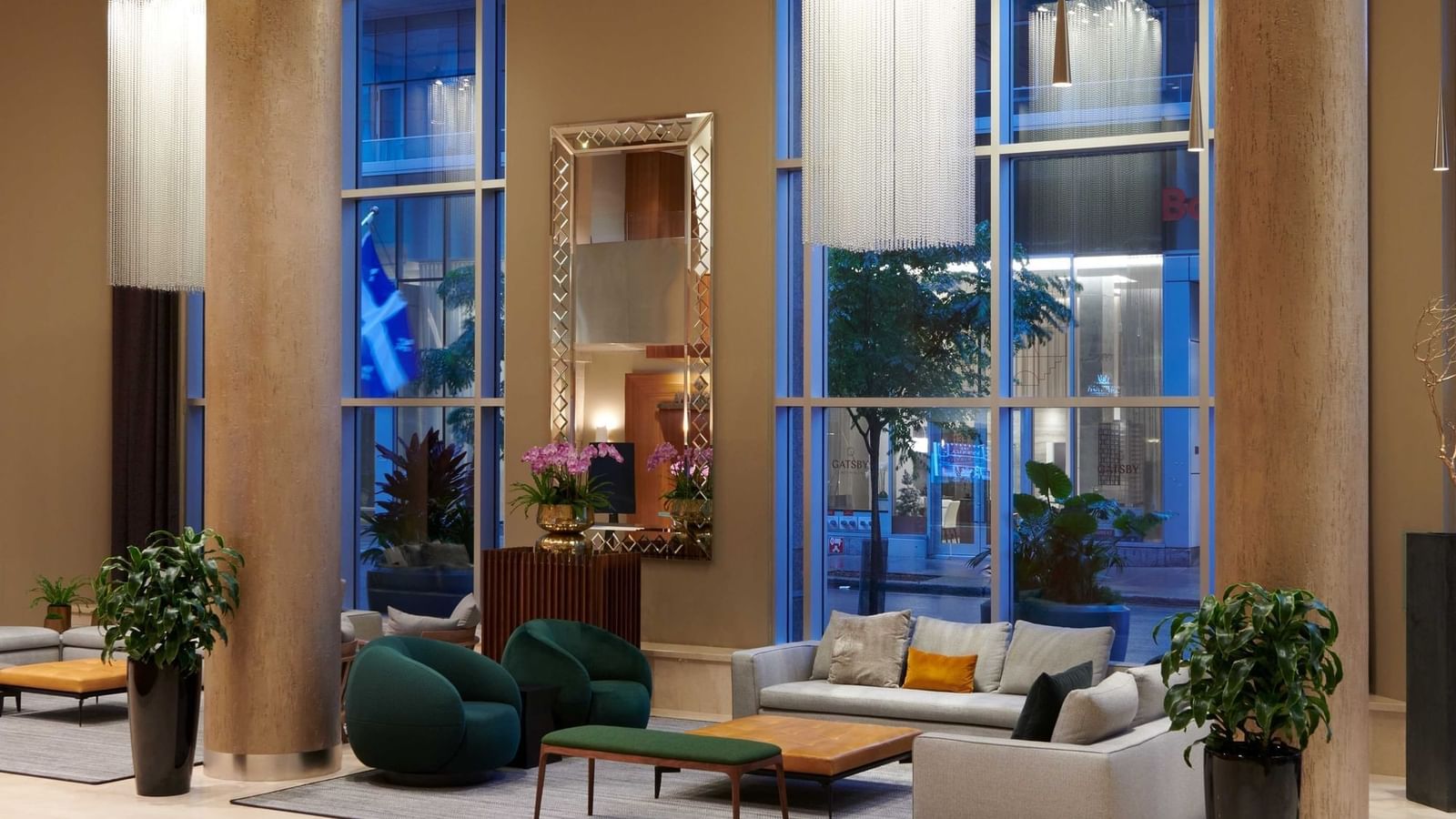 Lobby lounge with plush chairs and sofas by large windows under chandeliers at Warwick Le Crystal Montreal