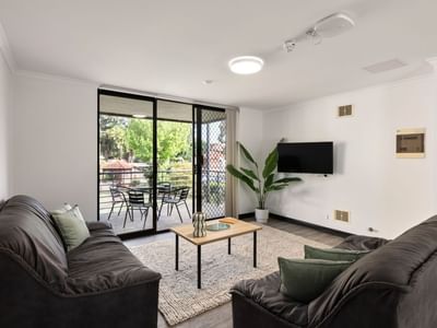 Two couches with coffee table and balcony with dining table at UniLodge at Curtin University - Erica Underwood House.