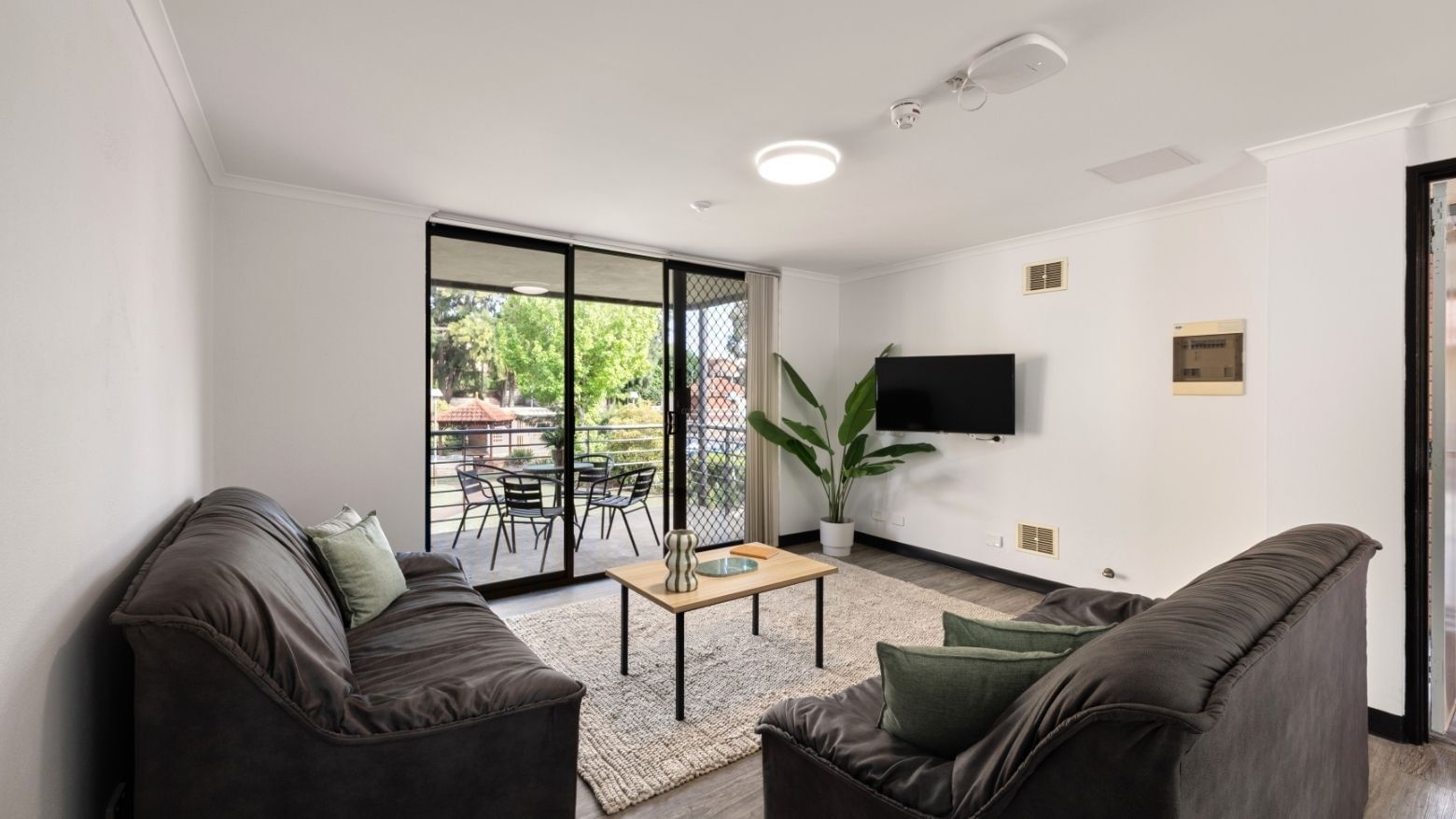 Two couches with coffee table and balcony with dining table at UniLodge at Curtin University - Erica Underwood House.