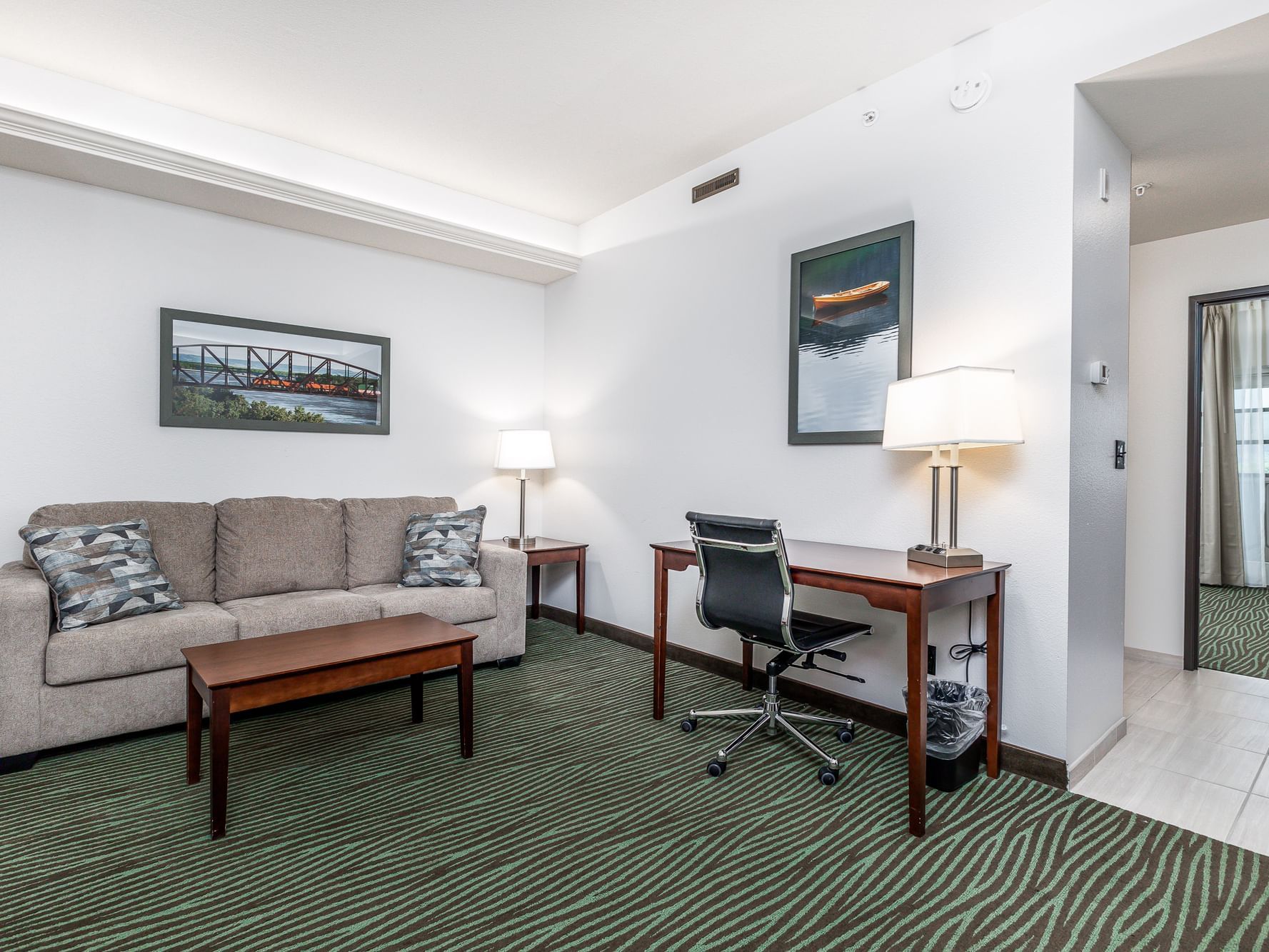 Work desk by the lounge area with carpeted floors and wall art in King Suite River View at Off Shore Resort