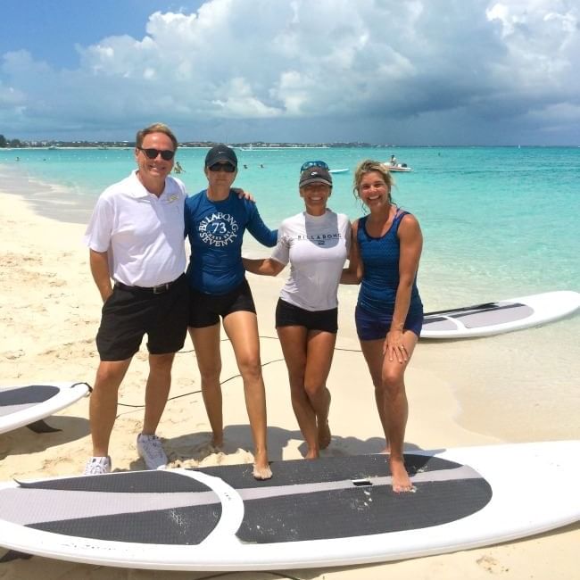 People posing with surfboards near The Somerset on Grace Bay