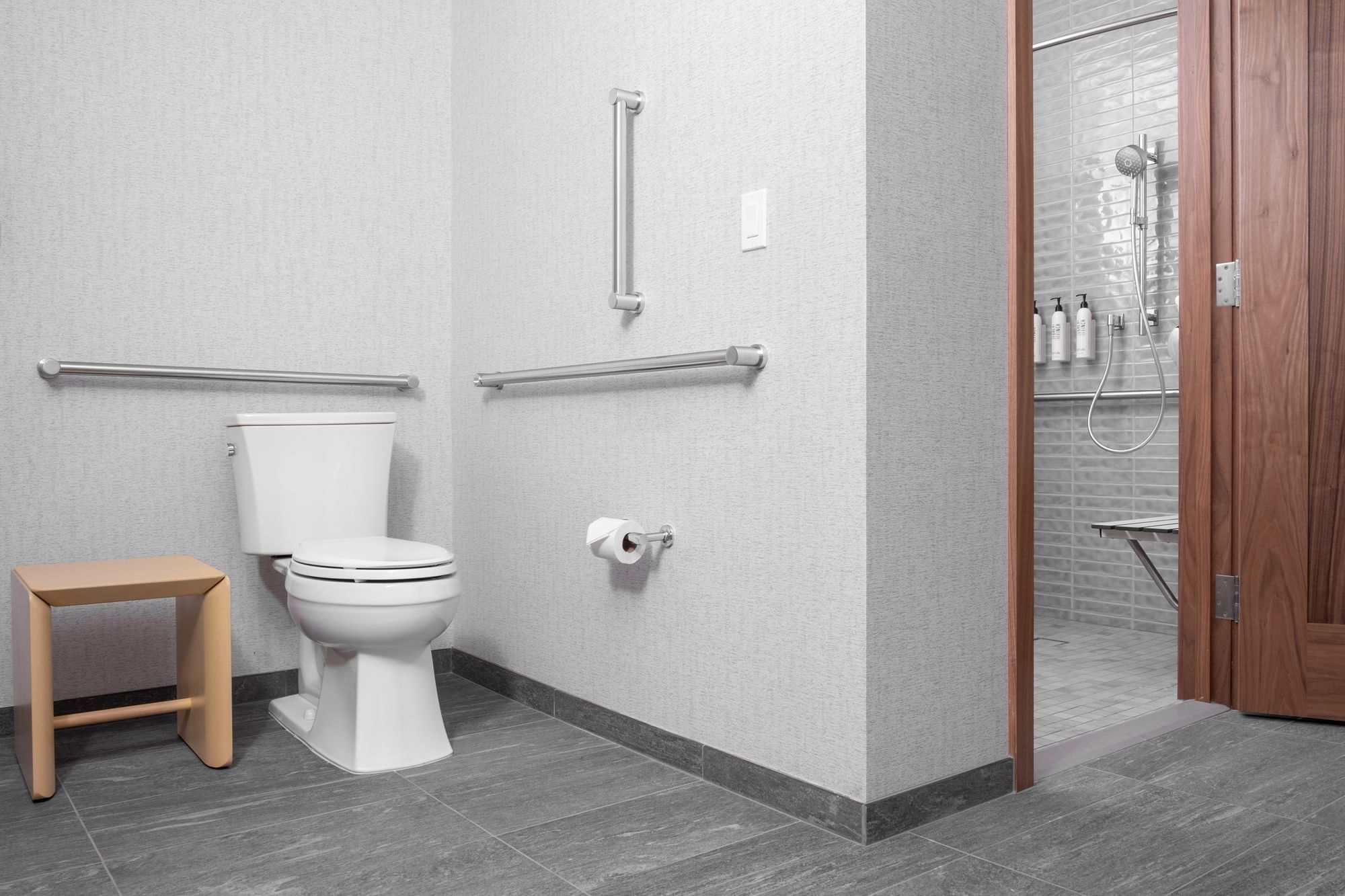 a bathroom with a toilet, grab bars, and a shower