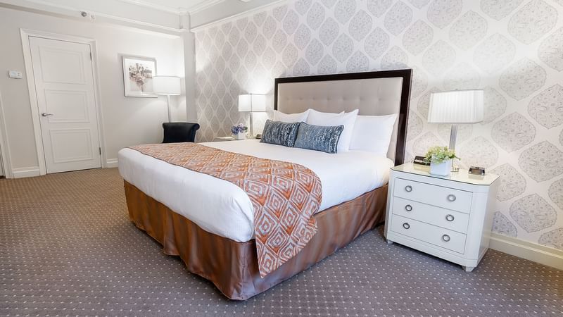 Bedside cupboards next to the bed with a cushioned headboard in Premier City View at Warwick New York