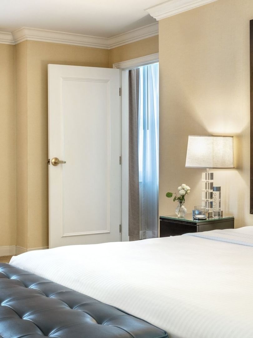 Bed with side table and couch near doorway and window in Specialty Suite at Warwick Allerton Chicago